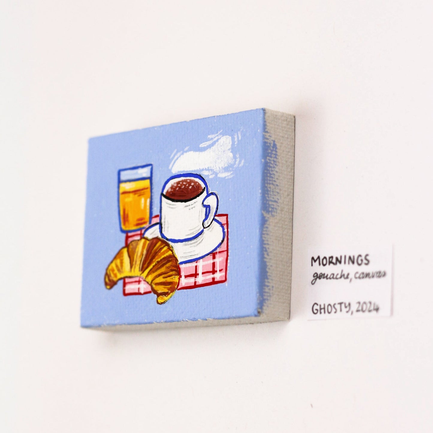 tiny gouache canvas featuring a croissant an orange juice and coffee