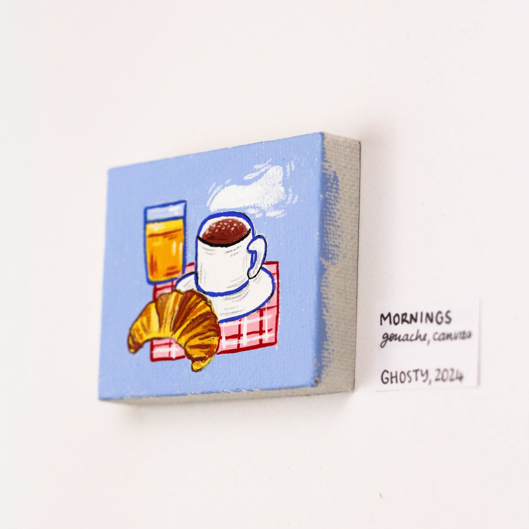 tiny gouache canvas featuring a croissant an orange juice and coffee